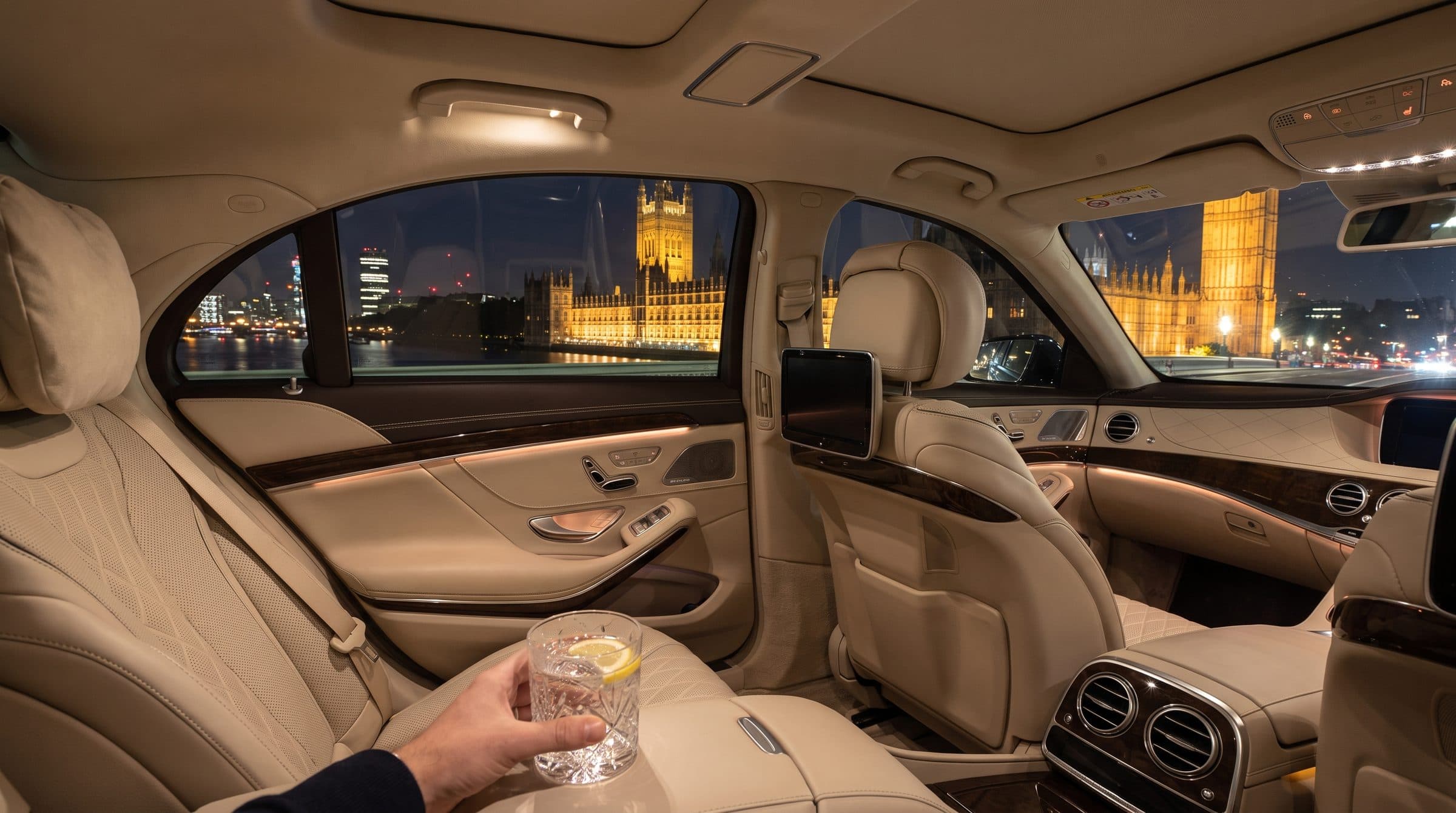 Back seat of a chauffeur car at night crossing Westminster Bridge with Parliament lit up